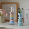 A set of handcrafted soy wax aromatherapy candles in pastel colors displayed on a white shelf.