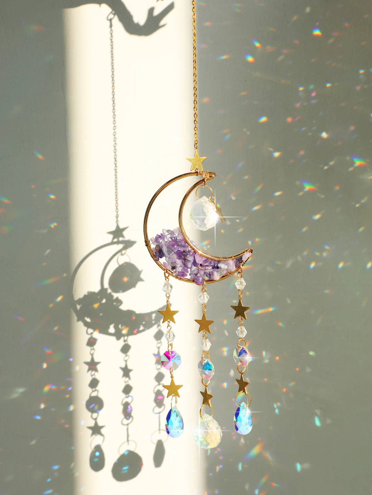 A handcrafted gold pendant featuring a purple moon crystal and dangling prism charms.