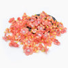 A pile of small, pink-orange silk artificial flower heads used for weddings and crafts.