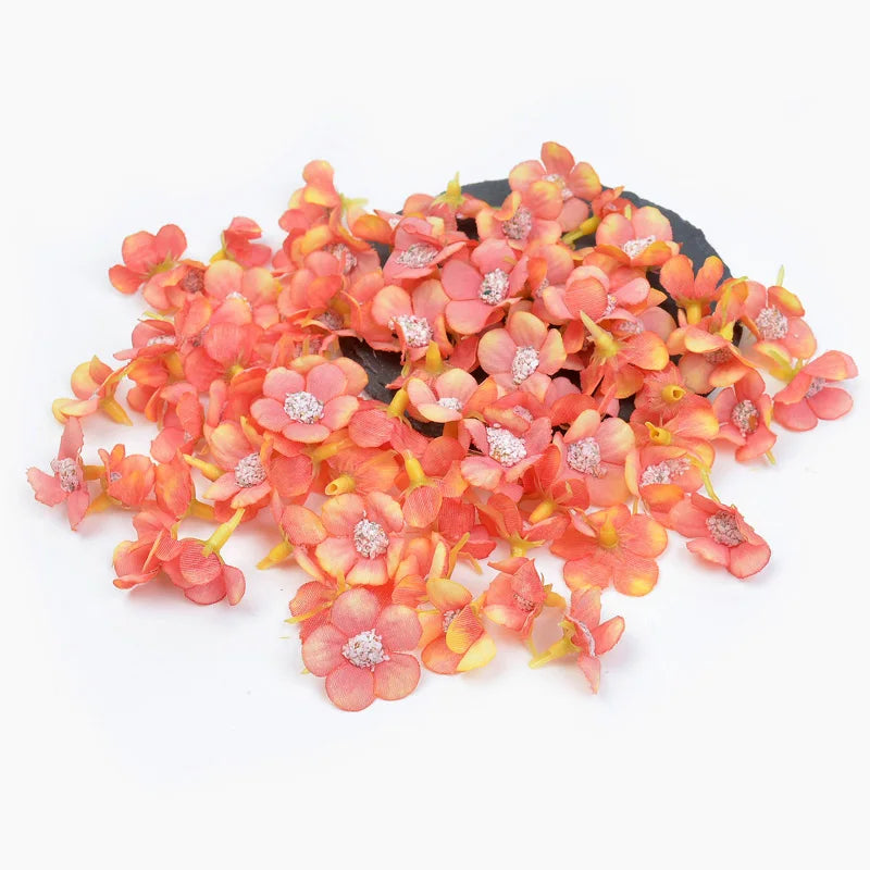 A pile of small, pink-orange silk artificial flower heads used for weddings and crafts.