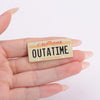 A gold-colored enamel pin shaped like a California license plate featuring the text OUTATIME The Golden State