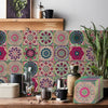 A close-up of colorful floral patterned self-adhesive tile wall stickers displayed on a wooden surface.