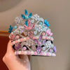 A silver crown adorned with pink, blue, and purple faux pearls and gemstones.