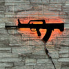 A black gun-shaped LED light fixture mounted on a stone wall, illuminated with an orange glow.