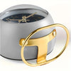 A minimalist Nordic alarm clock with a silver casing and gold accents, shown from the side.