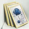 A set of three light wood picture frames displaying a blue watercolor flower print.