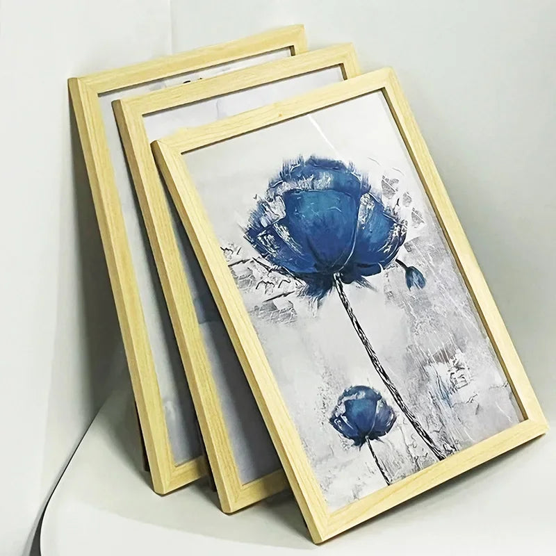 A set of three light wood picture frames displaying a blue watercolor flower print.