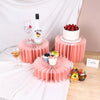 A display of pink decorative cake stands featuring a bottle of Malibu and cupcakes with fresh strawberries.