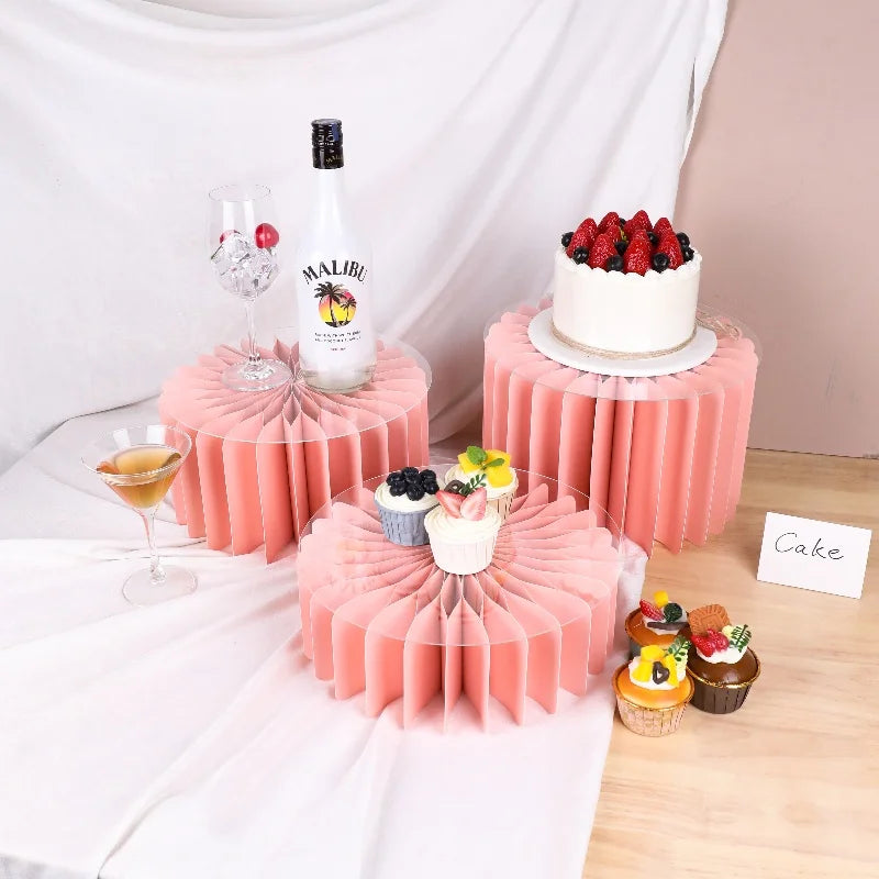 A display of pink decorative cake stands featuring a bottle of Malibu and cupcakes with fresh strawberries.