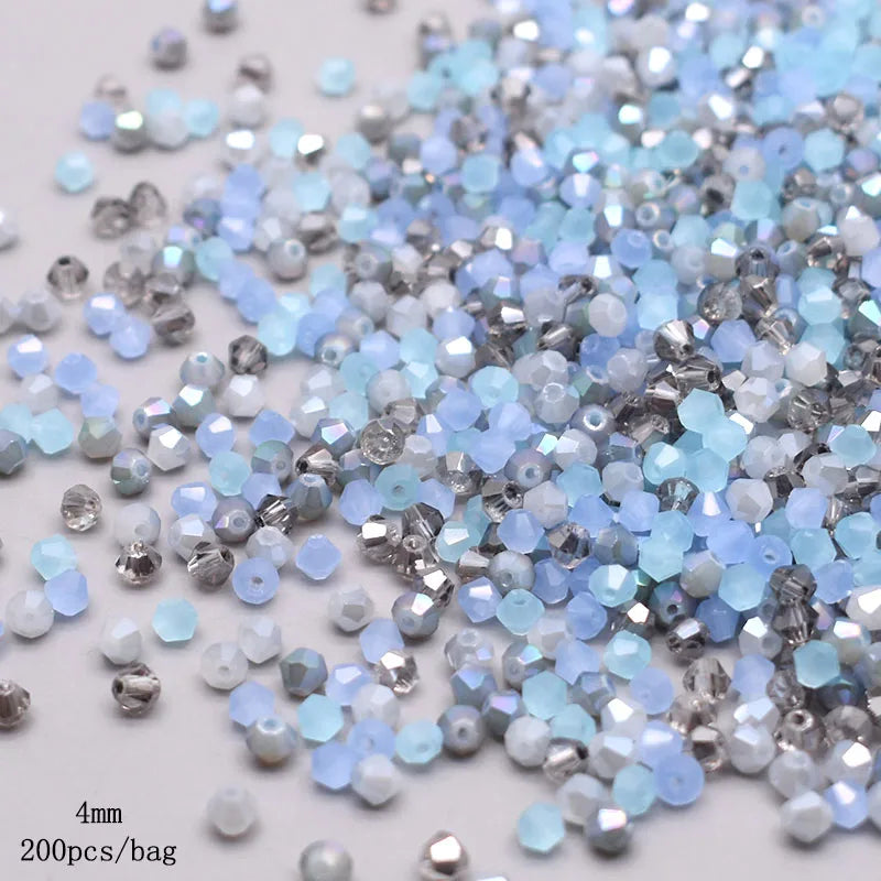 A pile of faceted bicone glass beads in mixed light blue and silver colors for jewelry making