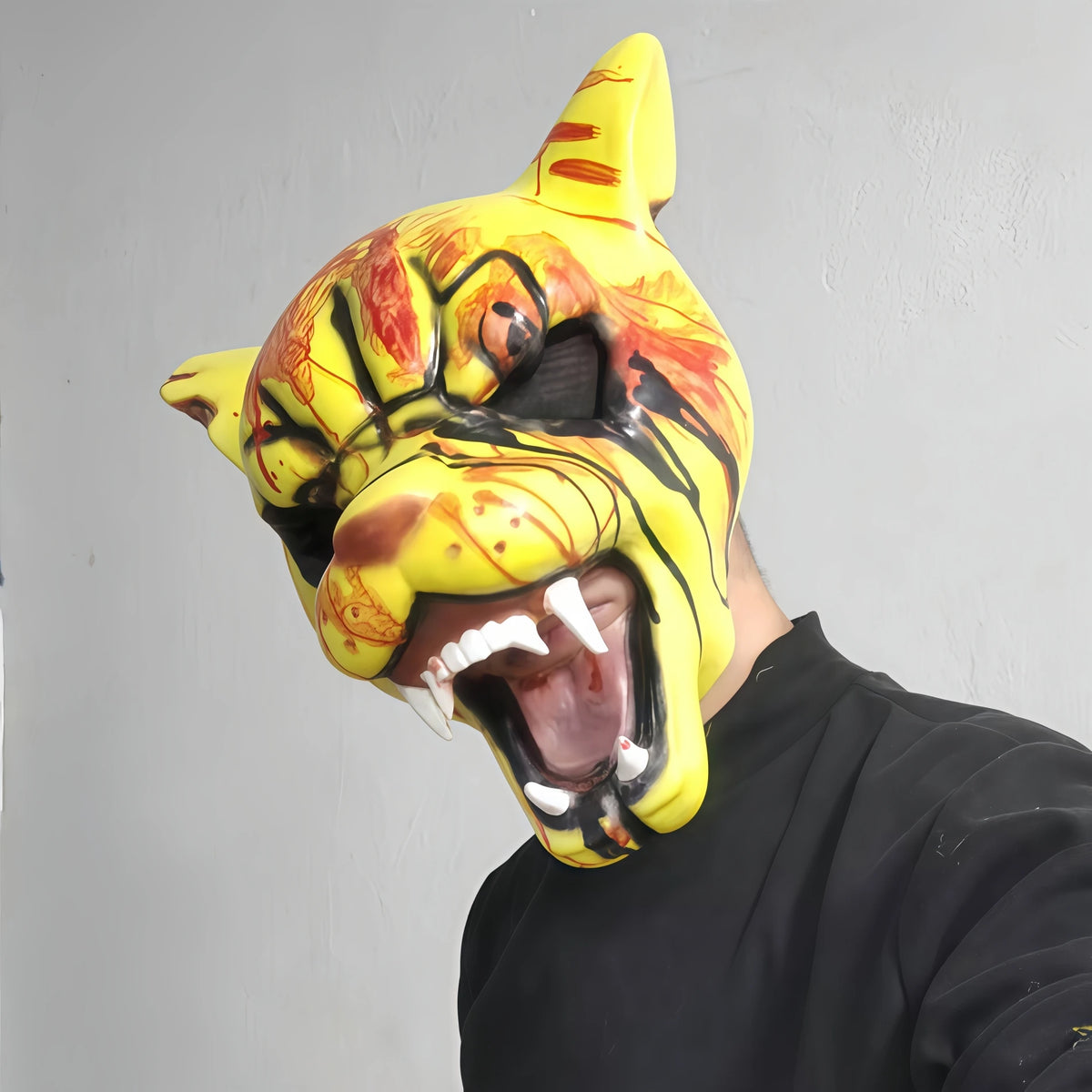 A close-up of a yellow and orange bloody tiger horror latex mask being worn by a person.
