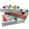 A collection of colorful articulated baby dragon figurines displayed in open boxes with text related to efforts and love.