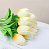 Un ramo de flores artificiales de tulipanes blancos y amarillos sobre una superficie blanca.