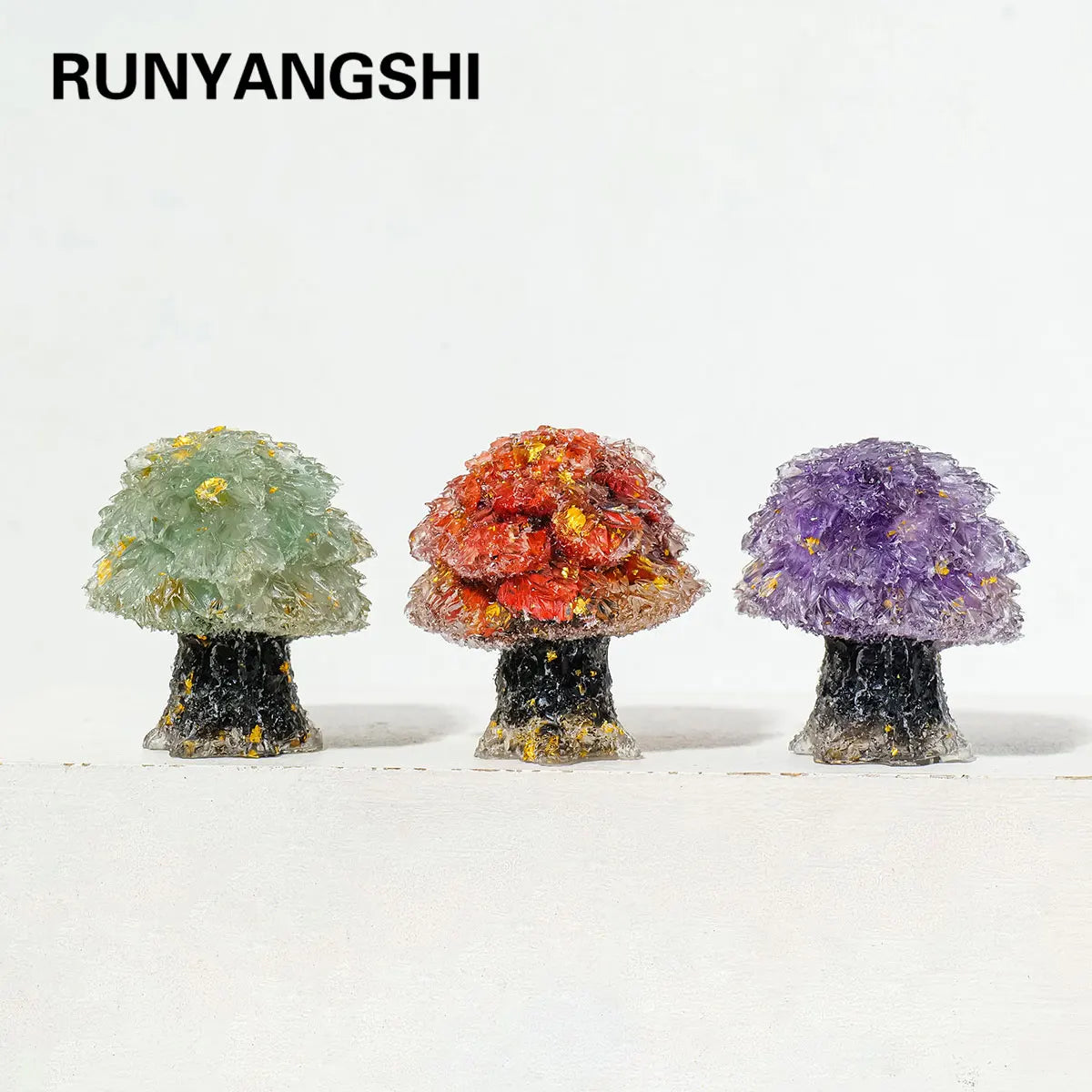 Three natural crystal mushroom tree sculptures displaying green, orange, and purple hues.