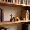 A small wooden Easter empty tomb scene decoration featuring a cross and a tomb structure on a wooden shelf.