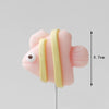 A pink cake topper featuring a crab, with a yellow striped element, shown against a light gray background.