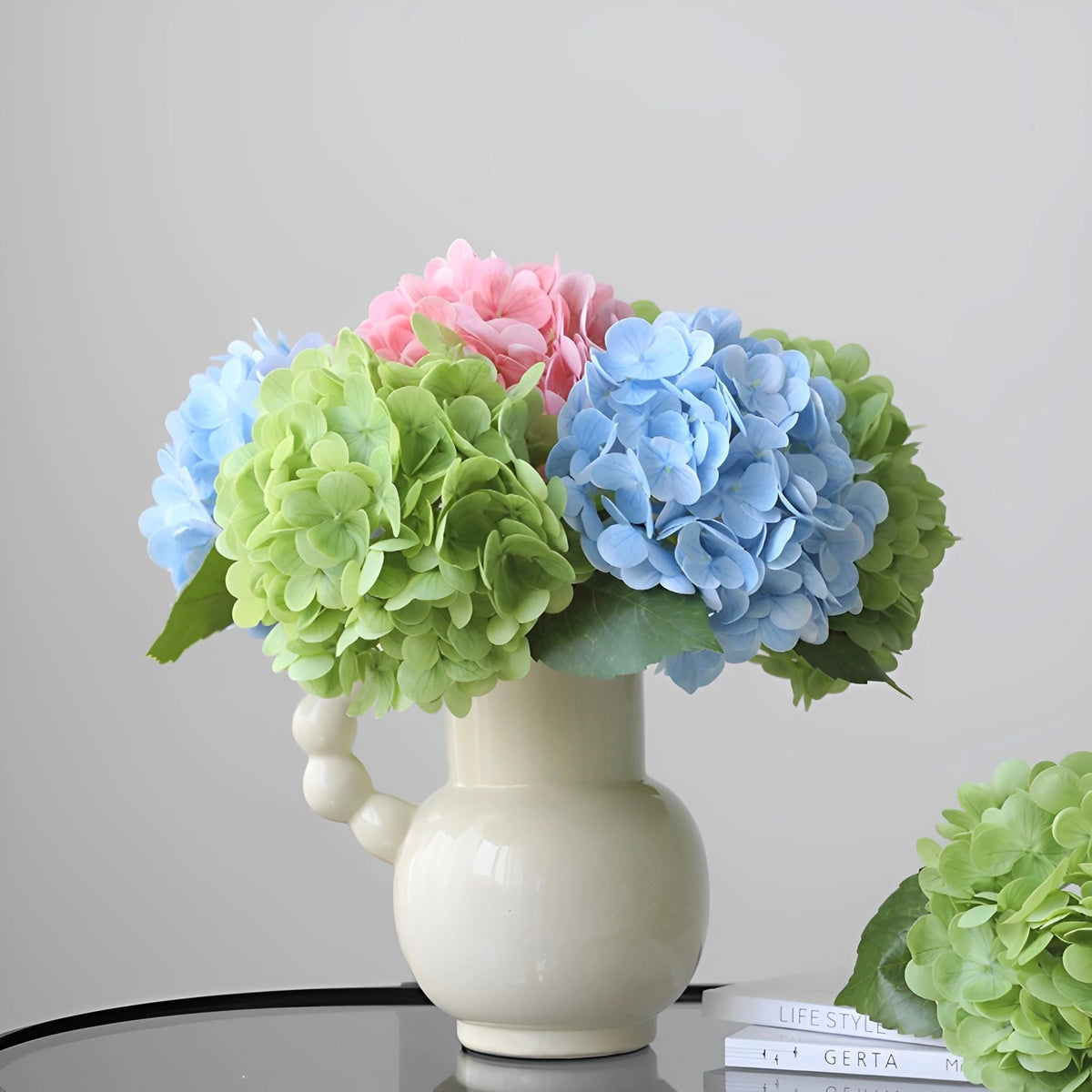 A bouquet of artificial hydrangea stems in shades of pink, blue, and green arranged in a white vase.