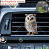 A decorative acrylic owl figurine clipped onto a car air vent.