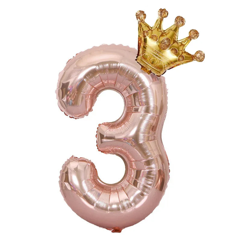 A rose gold foil balloon shaped like the number 3 with a gold crown on top.