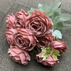 A bouquet of nine realistic silk roses in dusty rose and mauve tones with green foliage.