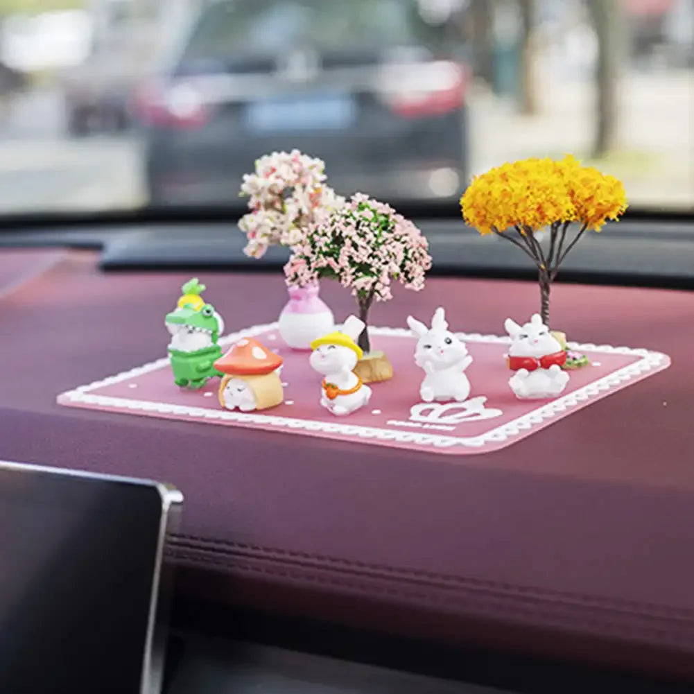A display of cute mini tree car dashboard ornaments featuring animals and flowers on a pink tray.