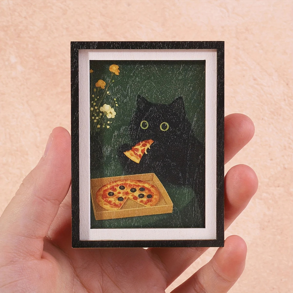 A framed print featuring a black cat and pizza design on a dark green background.
