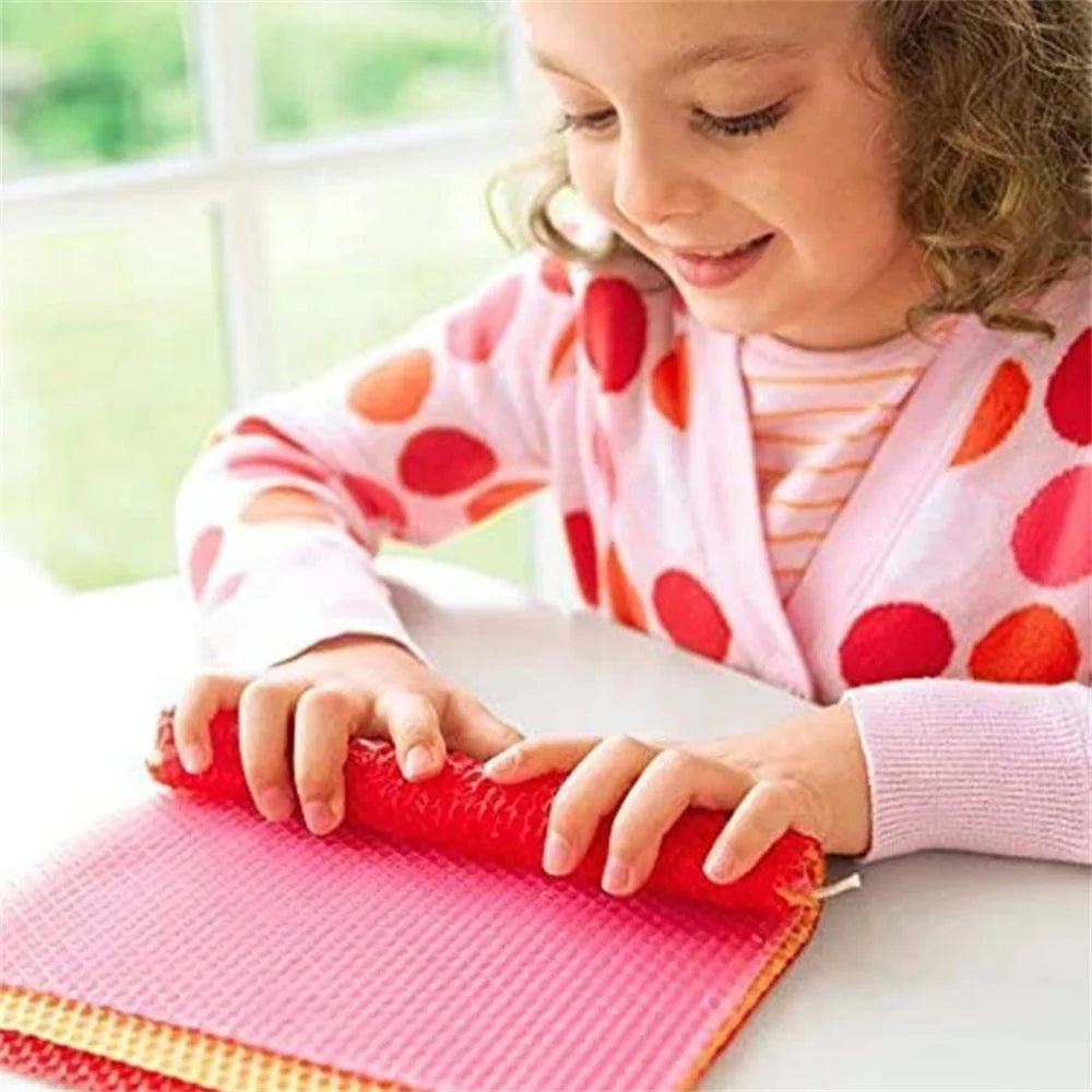 A young girl is using a red tool to press honeycomb beeswax into a pink mat for a DIY candle kit.