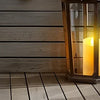 A display of various glass and ceramic lanterns holding realistic flickering LED candles on a wooden surface.
