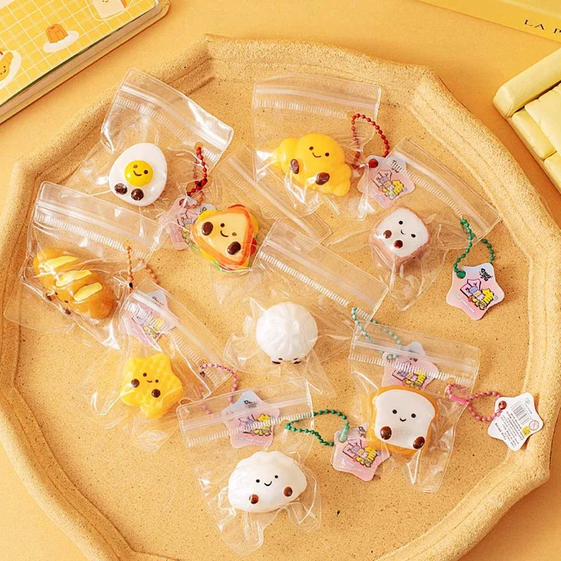 A collection of cute cartoon food squeeze toys in various shapes and colors packaged in clear plastic pouches on a light yell