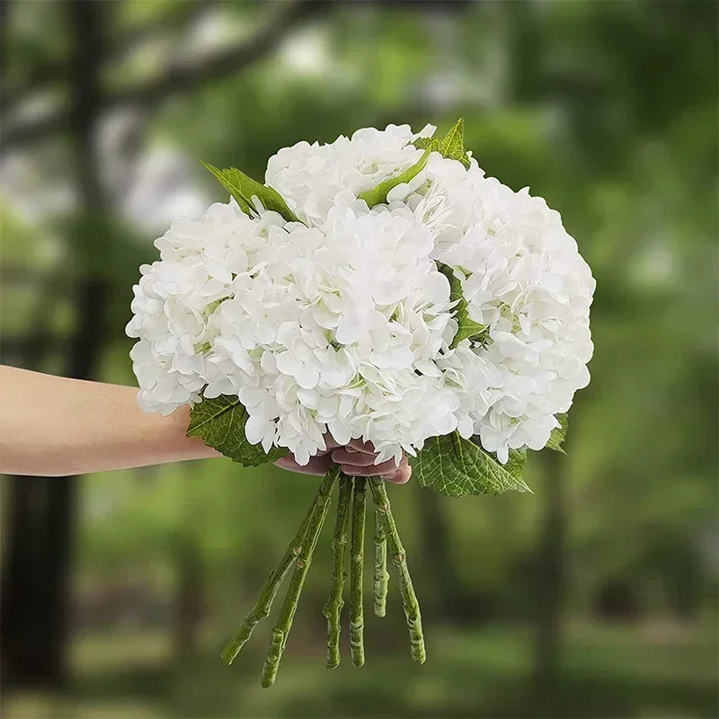 A bouquet of large white artificial hydrangea flowers with green stems.