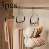 A set of metal hat storage hooks hanging on a wooden bar, with various light pink and beige hats displayed below.