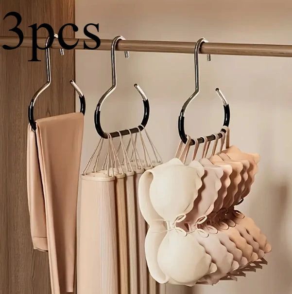 A set of metal hat storage hooks hanging on a wooden bar, with various light pink and beige hats displayed below.