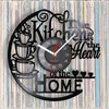 A black wall clock design featuring a coffee cup silhouette and text that reads Kitchen is the Heart of the Home