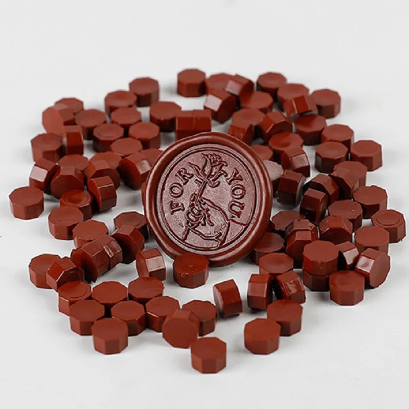 A pile of reddish-brown wax sealing beads for custom stamps, scattered on a white surface.