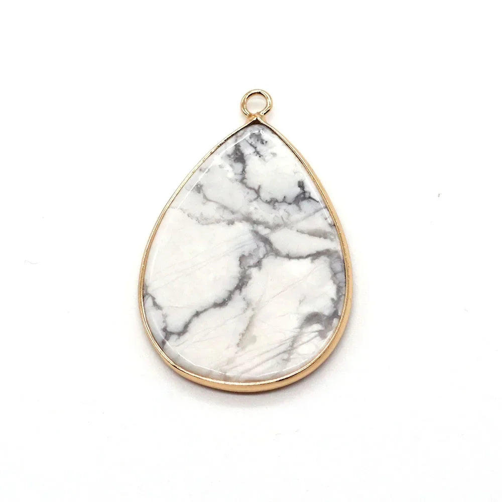 A teardrop-shaped pendant charm made of white marble with gray veining and a gold-colored bail.