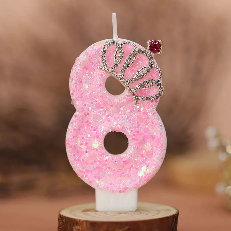 Pink glitter number eight birthday candle with a crown topper on a wooden stand