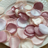 A collection of pink and blush silk rose petals arranged on a white plate for weddings and events.