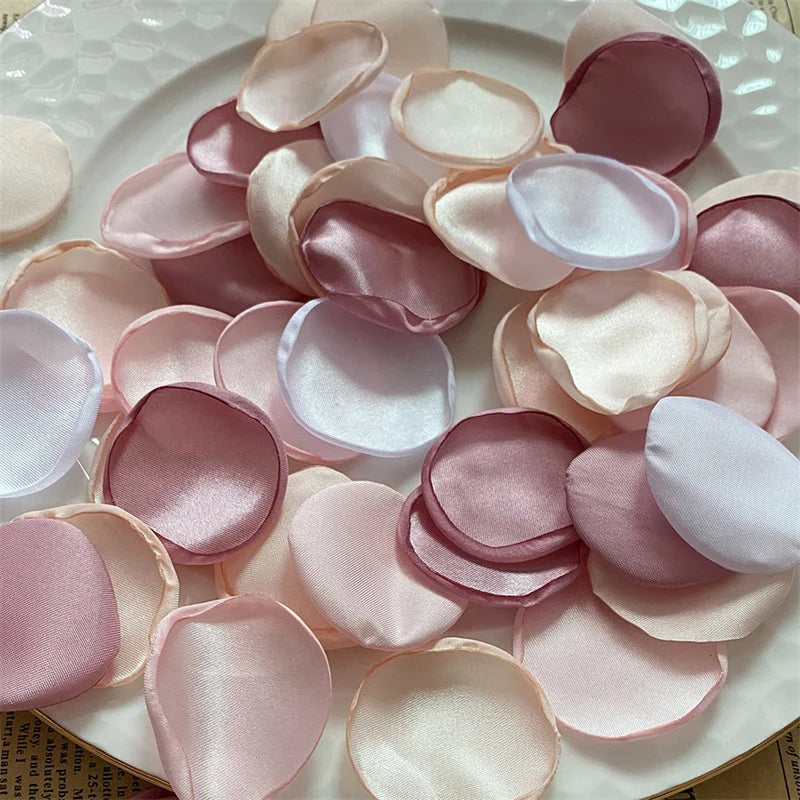 A collection of pink and blush silk rose petals arranged on a white plate for weddings and events.