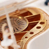 A close-up of a gold hand-crank music box featuring a spinning ballerina and decorative elements.