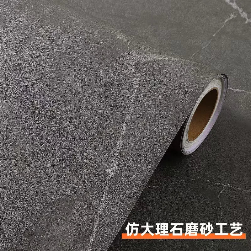 Roll of matte marble self-adhesive waterproof wallpaper being unrolled on a dark surface