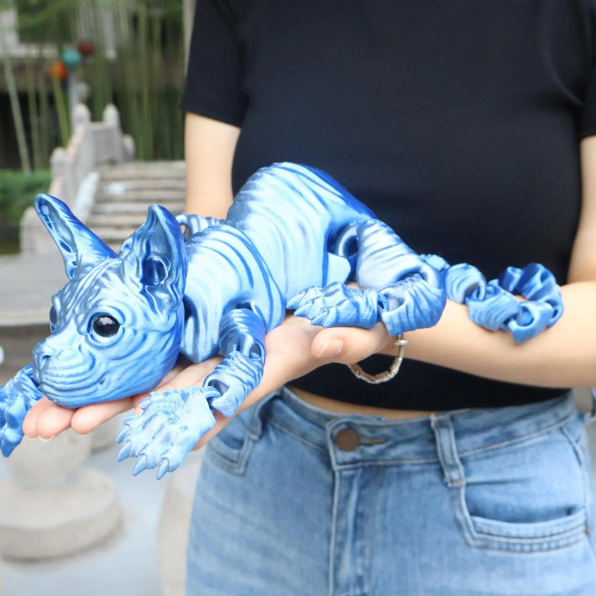 A hand holds a realistic blue Sphynx cat fidget toy with wrinkled skin and detailed features.