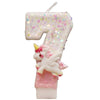 Vela de cumpleaños con forma de 7 cubierta de purpurina y una pequeña figura de unicornio blanco.