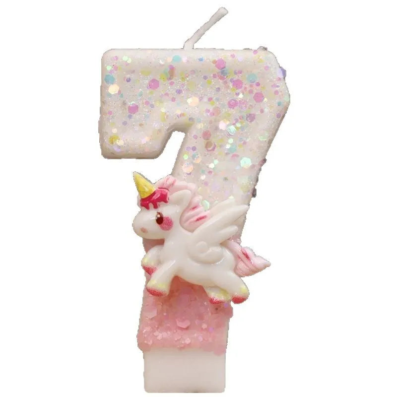 Vela de cumpleaños con forma de 7 cubierta de purpurina y una pequeña figura de unicornio blanco.