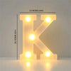 A glowing yellow LED letter K sign with individual lights, displayed against a light background.