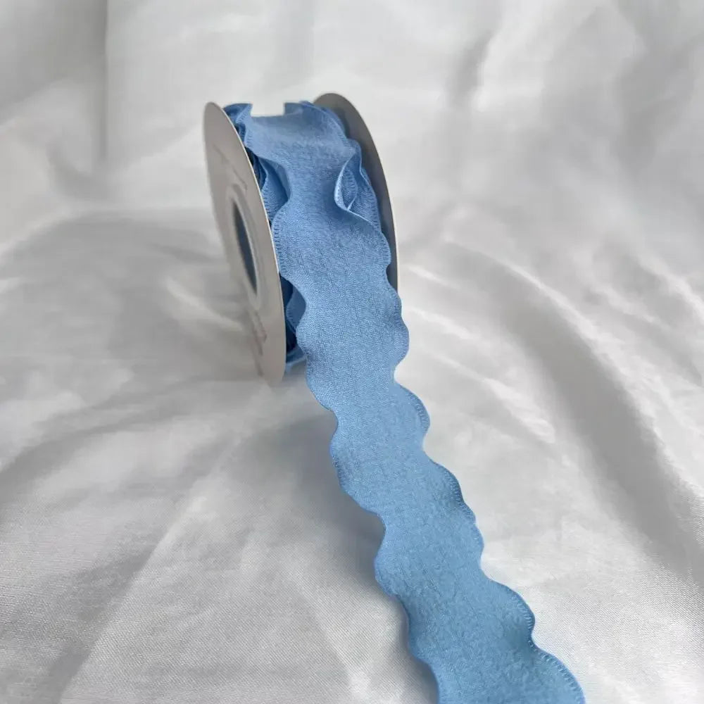 A roll of light blue decorative fishtail yarn ribbon lying on a white surface.