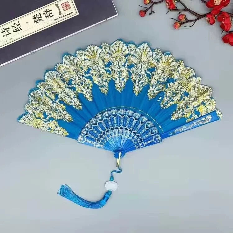 A blue and gold folding fan with intricate traditional Chinese designs displayed on a light gray surface.