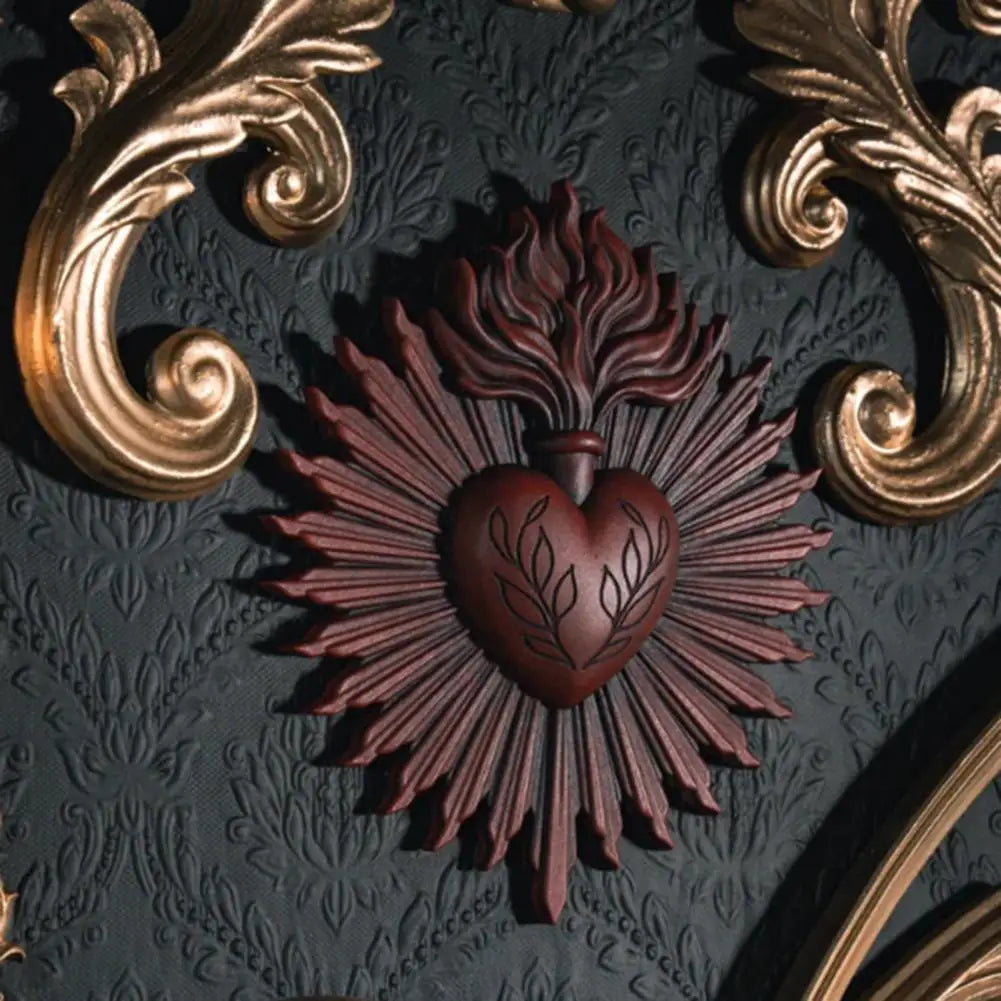 A dark wall plaque featuring a reddish-brown sacred heart design surrounded by radiating lines and ornate gold scrollwork.