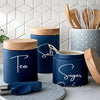 Blue kitchen canisters with white vinyl labels for tea, salt, and sugar storage