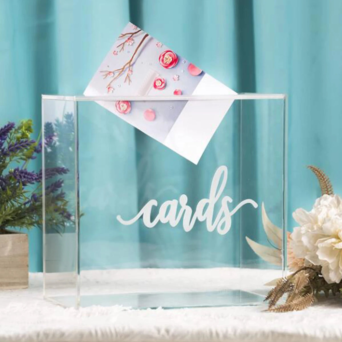 A clear acrylic box displays a stack of cards with pink and red floral accents on a white background.