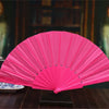 A bright pink lace folding hand fan displayed on a dark wooden surface.